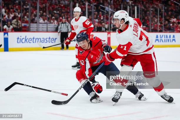 Martin Fehervary of the Washington Capitals looses his stick in an attempt to block the shot of Dylan Larkin of the Detroit Red Wings during the...