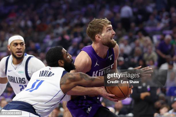 Domantas Sabonis of the Sacramento Kings is guarded by Kyrie Irving of the Dallas Mavericks in the first half at Golden 1 Center on March 26, 2024 in...