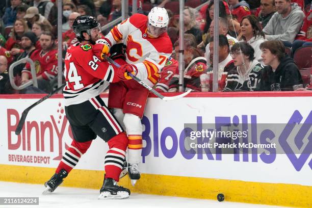 Seth Jones of the Chicago Blackhawks checks Martin Pospisil of the Calgary Flames into the boards during the third period at the United Center on...