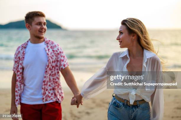 romantic sunset beach stroll: caucasian couple embracing love and serenity along the tranquil coastline - chonburi province stock pictures, royalty-free photos & images