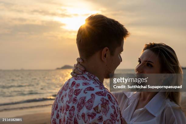 romantic sunset beach stroll: caucasian couple embracing love and serenity along the tranquil coastline - chonburi province stock pictures, royalty-free photos & images