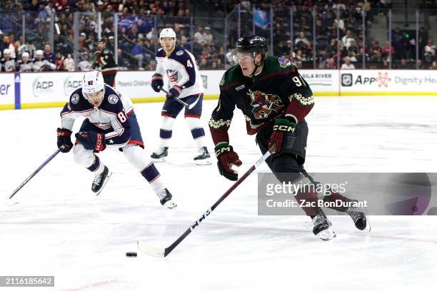 Josh Doan of the Arizona Coyotes skates with the puck against Mikael Pyyhtia of the Columbus Blue Jackets during the second period at Mullett Arena...