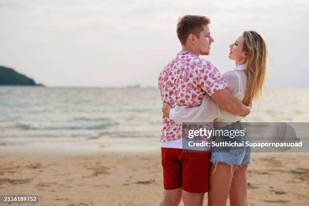 romantic sunset beach stroll: caucasian couple embracing love and serenity along the tranquil coastline - chonburi province stock pictures, royalty-free photos & images