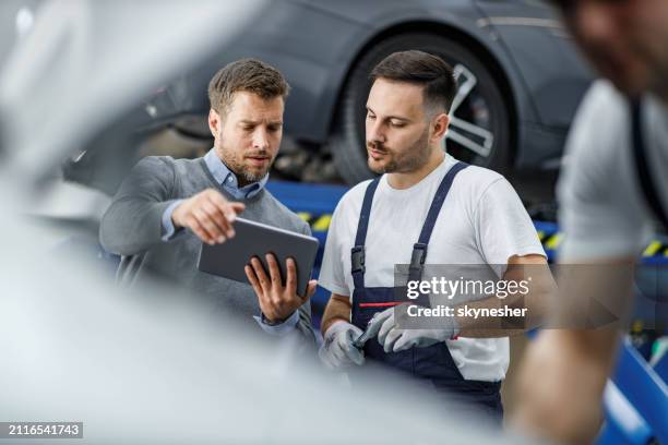male customer and auto mechanic using touchpad in a workshop. - auto shop manager stock pictures, royalty-free photos & images
