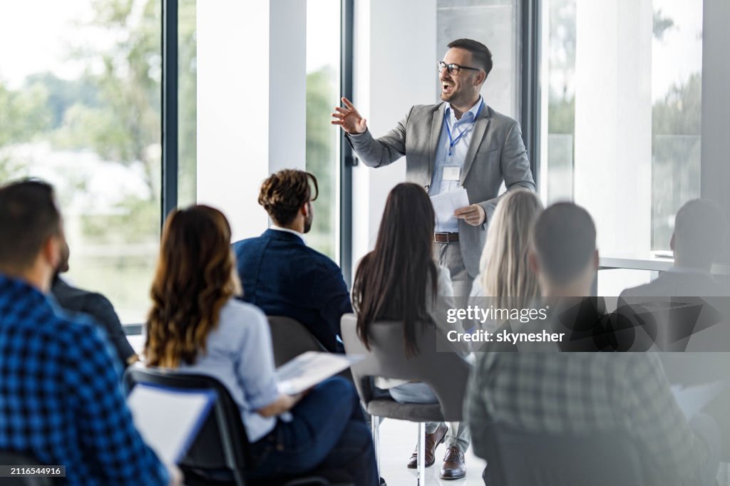 Happy business leader talking to group of his colleagues on a seminar in board room.