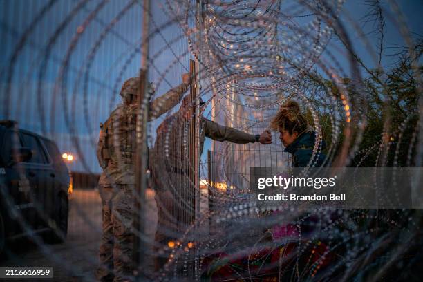 Eliana a migrant from Venezuela, holds her daughter Crismarlees while being denied entry after attempting to cross through concertina from the U.S....