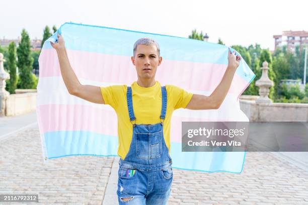 front portrait of homosexual person holding a transgender flag in the street in madrid - ftm stock-fotos und bilder