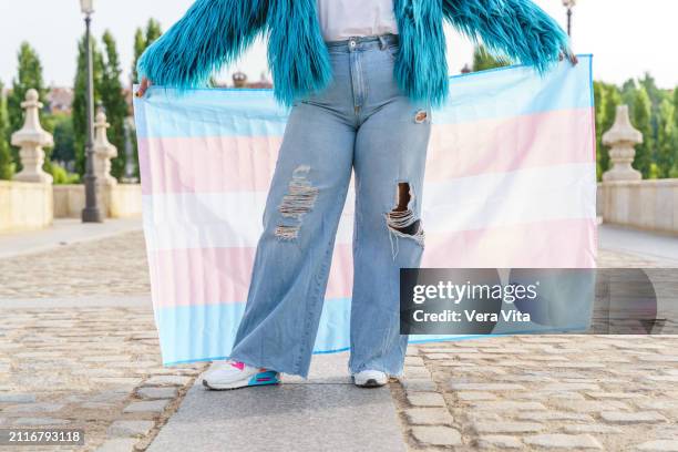 unrecognizable person holding a transgender flag in the street in madrid - transgender symbol stock pictures, royalty-free photos & images