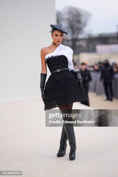 Jessica Aidi wears a black leather beret hat, a choker, a white asymmetric shirt, black elbow length leather gloves, a Dior leather thin belt, a...