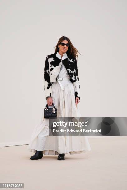 Bianca Brandolini wears sunglasses, a black and white cow pattern printed fluffy jacket , a white gathered / pleated long dress , a white leather...