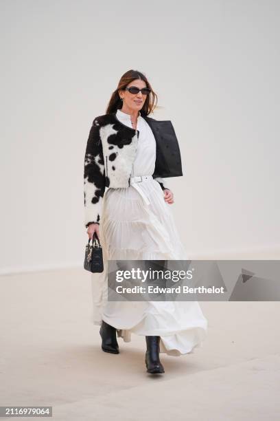 Bianca Brandolini wears sunglasses, a black and white cow pattern printed fluffy jacket , a white gathered / pleated long dress , a white leather...