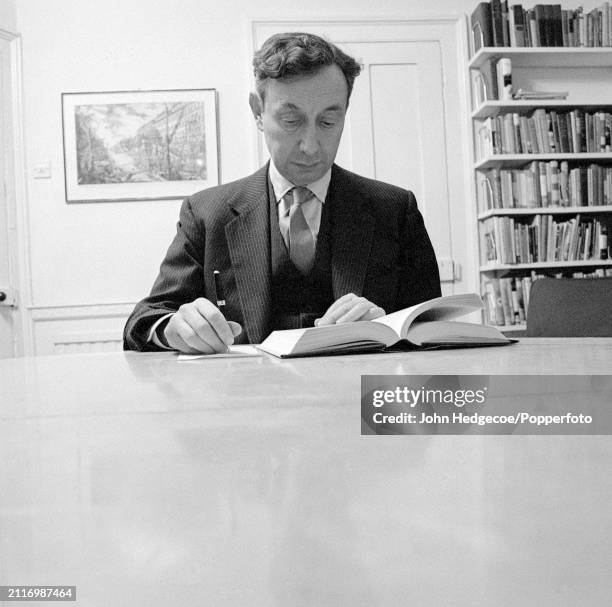 English philosopher A J Ayer seated at a table in a library in England in 1962.