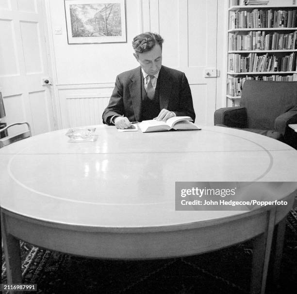 English philosopher A J Ayer seated at a table in a library in England in 1962.