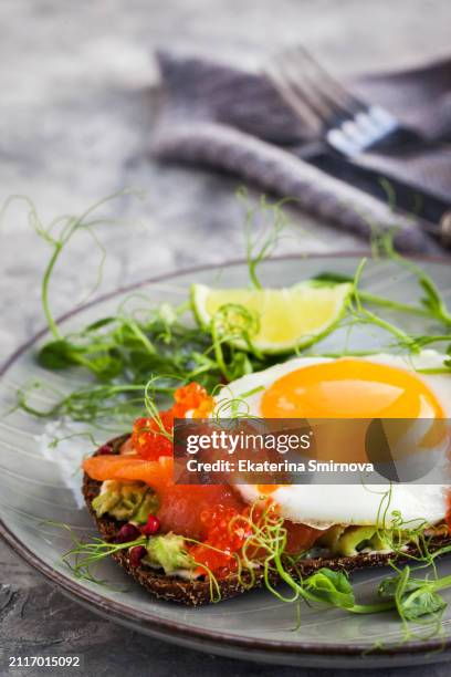 fried egg, salted salmon, red caviar and avocado on rye crisp toast - crispbread stock pictures, royalty-free photos & images