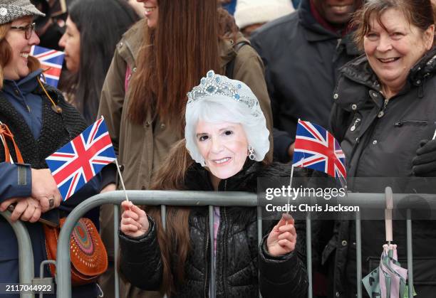Well-wisher wears a mask and holds Union Jack flags as she awaits the arrival of Queen Camilla during her visit to the Farmers' Market on March 27,...