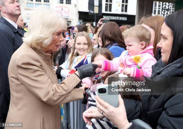 Queen Camilla holds a toddlers hand as she meets well-wishers during her visit to the Farmers' Market on March 27, 2024 in Shrewsbury, England.