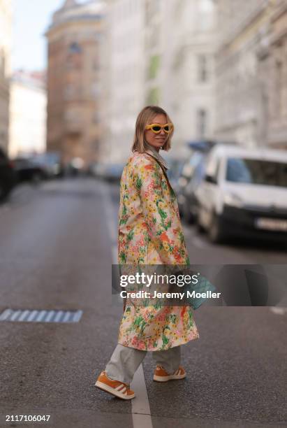 Karin Teigl seen wearing Loewe yellow sunglasses, Agolde light grey denim straight leg pants, Stine Goya yellow with colorful flower embroidered...