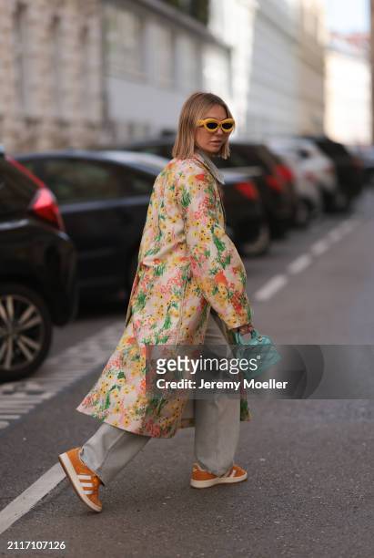 Karin Teigl seen wearing Loewe yellow sunglasses, Agolde light grey denim straight leg pants, Stine Goya yellow with colorful flower embroidered...
