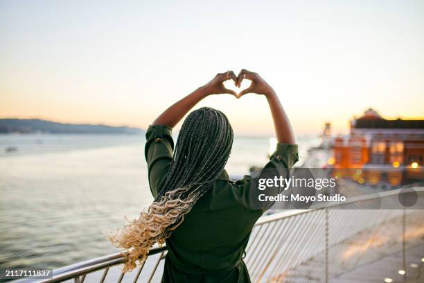vue arrière d’une femme avec des tresses blondes en forme de coeur avec les mains sur la promenade au coucher du soleil - image of heart shape photos et images de collection