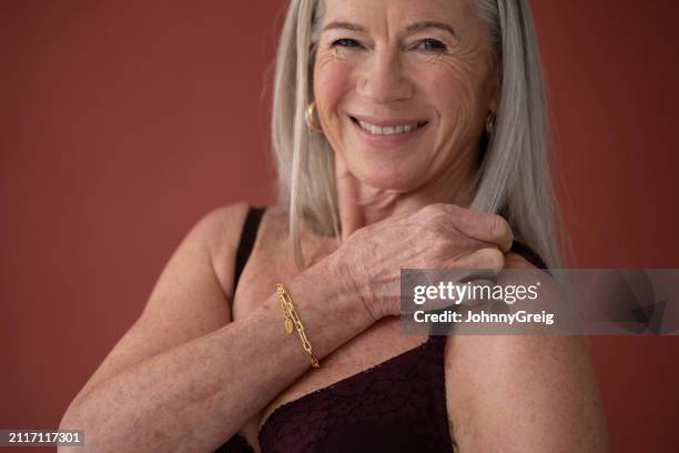 cheerful woman in early 70s securing lingerie strap - hoop earring stock pictures, royalty-free photos & images