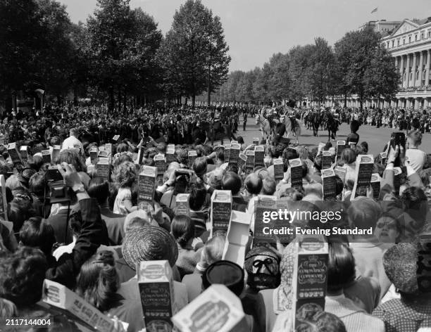 Crowds watch the Trooping the Colour ceremony with periscopes, The Mall, London, May 31st 1956. Queen Elizabeth II can be seen in the background on a...