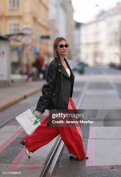 Karin Teigl seen wearing Miu Miu black oval sunglasses, gold necklaces, CYK white cotton basic top, Acne Studios black leather biker jacket, Adidas...