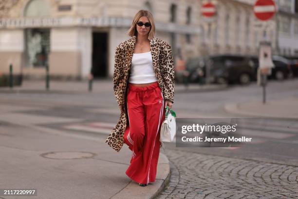 Karin Teigl seen wearing Miu Miu black oval sunglasses, gold necklaces, CYK white cotton basic top, H&M Studios leopard print pattern long coat,...