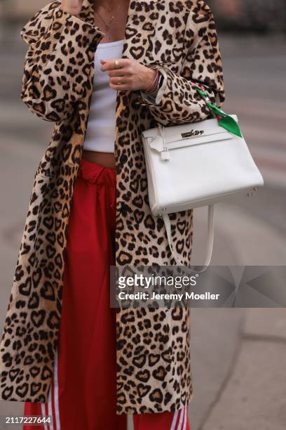 Karin Teigl seen wearing CYK white cotton basic top, H&M Studios leopard print pattern long coat, Adidas red long wide leg track pants, Hermès white...