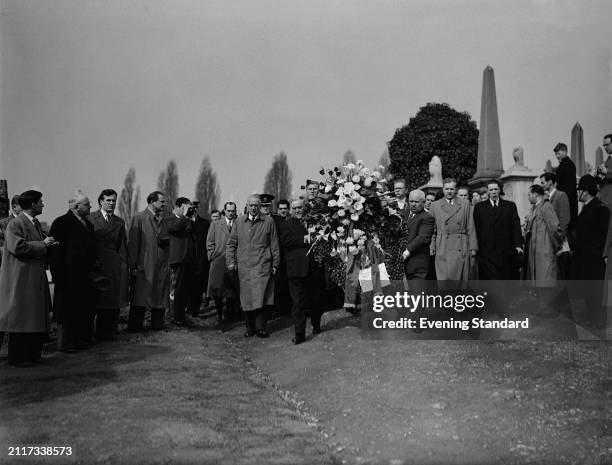 Soviet Premier Nikolai Bulganin left, and head of state Nikita Khrushchev right, carry a wreath together surrounded by a crowd of people at Highgate...
