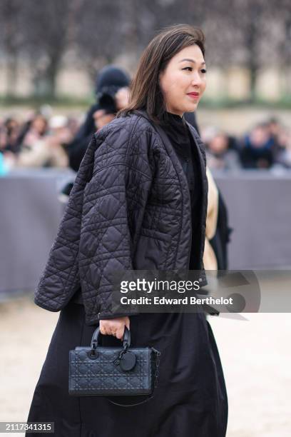 Guest wears a black quilted jacket , a Dior bag, a skirt, outside Dior, during the Womenswear Fall/Winter 2024/2025 as part of Paris Fashion Week on...