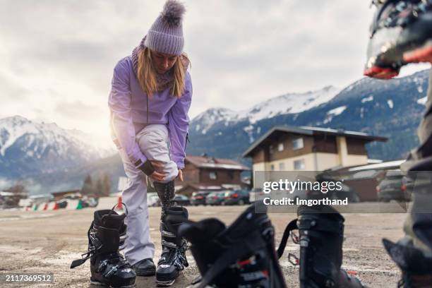 young woman putting on ski gear before skiing in european alps - skischoen stockfoto's en -beelden