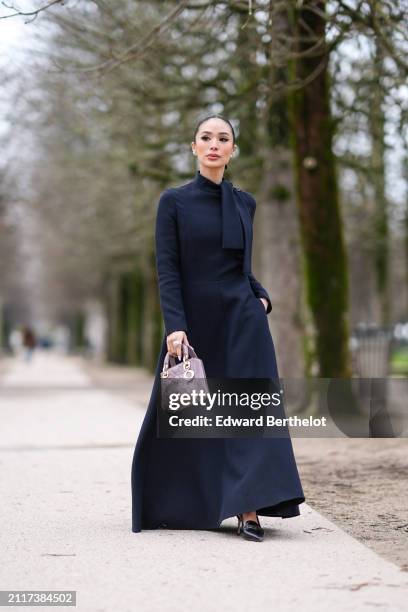 Heart Evangelista wears a dark navy blue turtleneck long maxi dress with shoulder pads, a mauve shiny quilted leather Lady Dior bag, black leather...