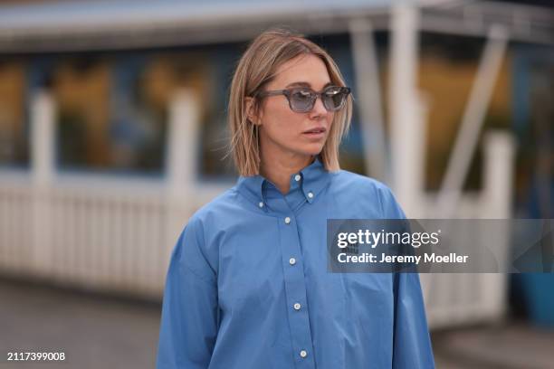 Karin Teigl seen wearing Rhude grey sunglasses and Miu Miu blue cotton cropped buttoned shirt, on March 23, 2024 in Munich, Germany.