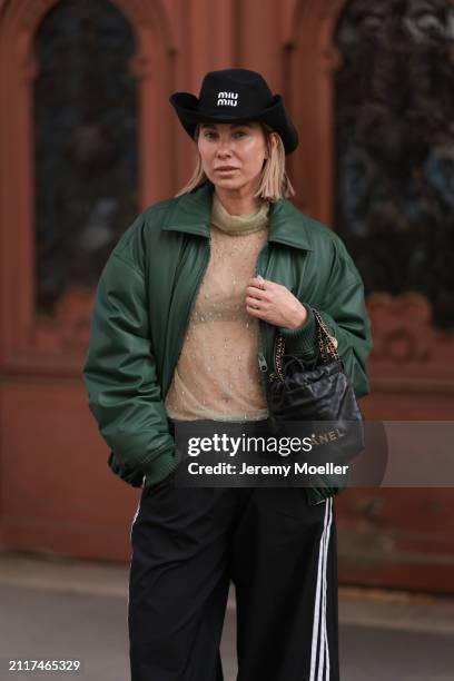 Karin Teigl seen wearing Miu Miu black cowboy hat, Zara beige transparent crystal high neck top, Zara dark green puffer bomber jacket, Adidas black...