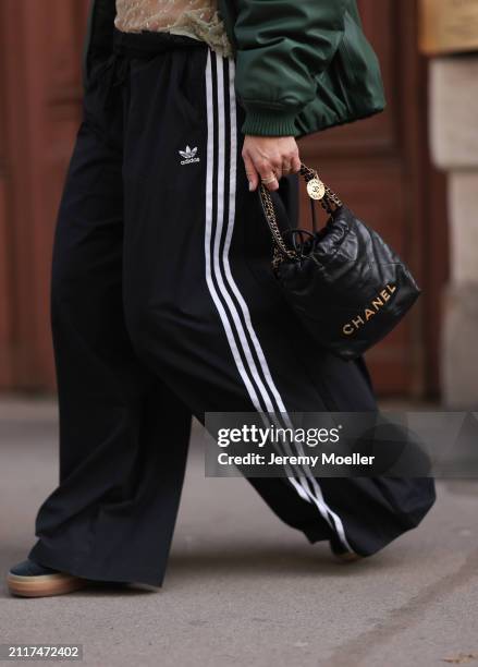 Karin Teigl seen wearing Zara dark green puffer bomber jacket, Adidas black wide leg track pants, Chanel black leather 22 mini bag, Bulgari Bzero...