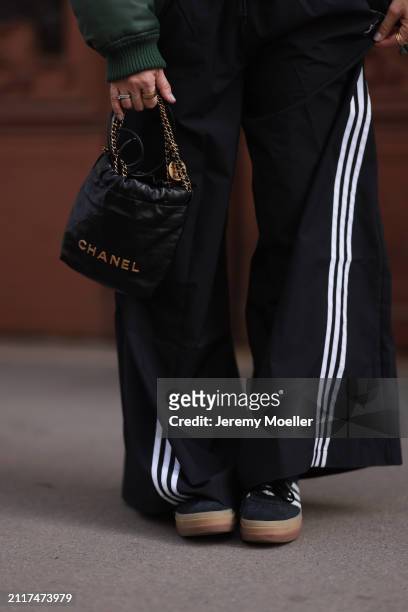 Karin Teigl seen wearing Adidas black wide leg track pants, Chanel black leather 22 mini bag, Oura gold fitness smart ring and Adidas black suede...