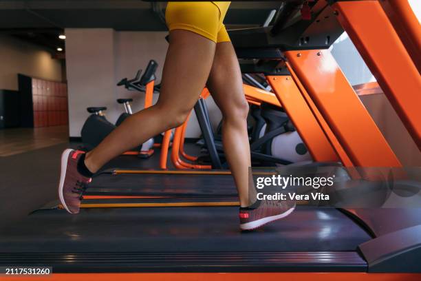 unrecognizable woman legs running in the treadmill with vitality indoors - vita shorts fotografías e imágenes de stock