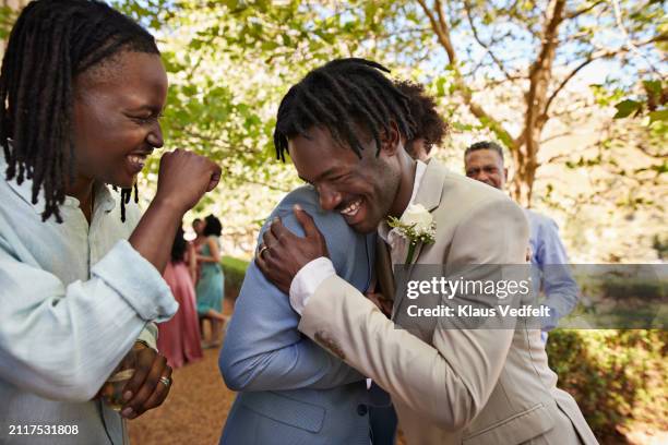 happy young groom hugging male friend - milestone stockfoto's en -beelden