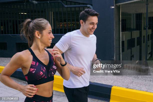 mid waist view of caucasian fitness couple running outdoors - vita shorts fotografías e imágenes de stock