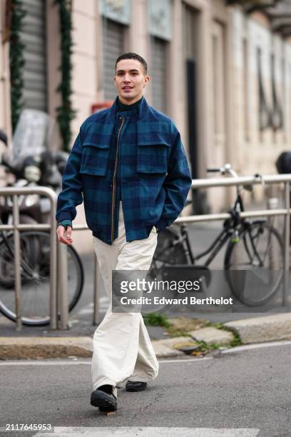 Guest wears a blue and green checkered / checked pattern printed jacket , white oversized flared pants , black leather shoes , outside K-WAY, during...