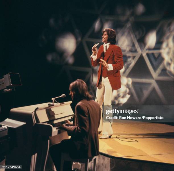 From left, Maurice Gibb and Barry Gibb of pop group The Bee Gees perform on the set of a pop music television show in London circa 1970.