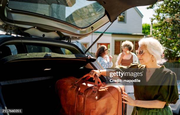 mujer madura empacando equipaje en un automóvil para un viaje por carretera con amigos - wanderlust concept fotografías e imágenes de stock