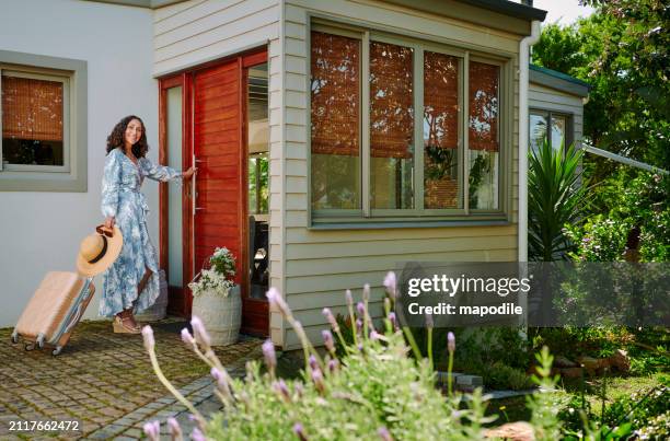 smiling mature woman arriving at the front door of her weekend vacation rental - bed and breakfast stock pictures, royalty-free photos & images