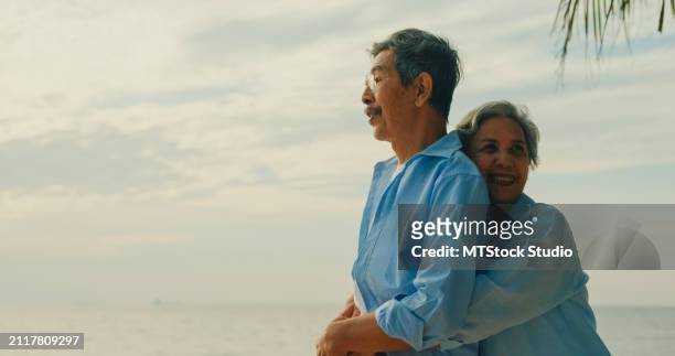 asian elderly cheerful couple smiling happily while embracing on beach enjoying the sea view. a happy senior adult people enjoy the travel lifestyle after retirement. - mes stock pictures, royalty-free photos & images