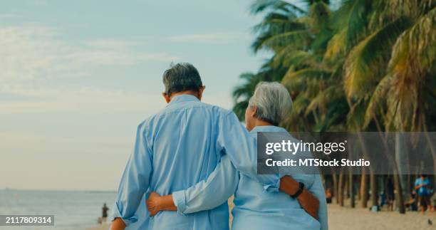 asian elderly cheerful couple smiling happily while embracing and walking on beach enjoying the sea view. a happy senior adult people enjoy the travel lifestyle after retirement. - mes stock pictures, royalty-free photos & images