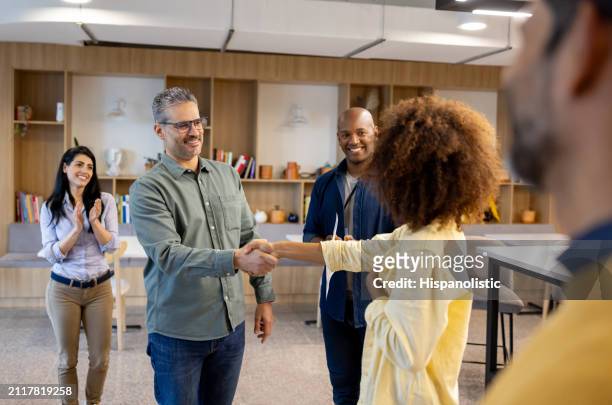 boss handshaking the hand of his new hire at the office - hispanolistic stock pictures, royalty-free photos & images