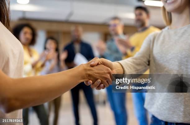 business women handshaking at the office - hispanolistic stock pictures, royalty-free photos & images