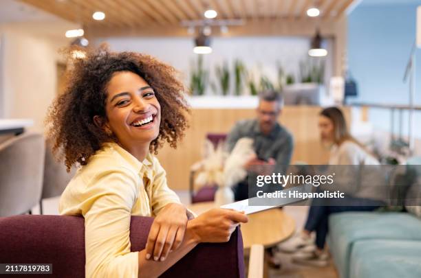 happy businesswoman working at the office using a digital tablet and smiling - hispanolistic stock pictures, royalty-free photos & images