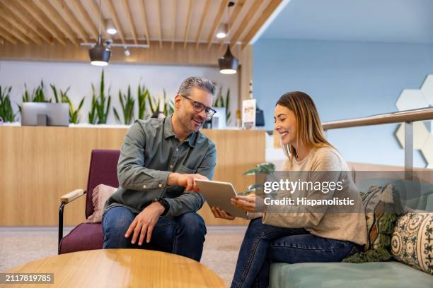 happy business people working together at the office using a digital tablet - hispanolistic stock pictures, royalty-free photos & images