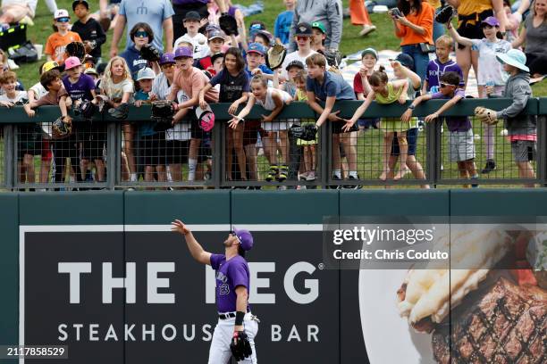 Kris Bryant of the Colorado Rockies tosses a ball to fans before the third inning of a spring training game against the Milwaukee Brewers at Salt...